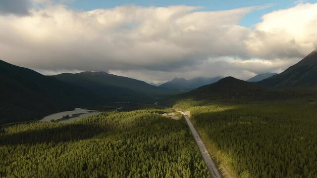 View of Scenic Road surrounded by Forest Valley, Mountains and Industry at Sunrise in Canadian Nature. Aerial Drone Shot. Taken near Stewart-Cassiar Highway, Northern British Columbia, Canada.