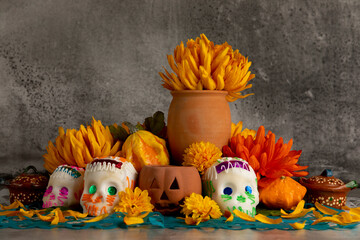 Sugar skulls used for "dia de los muertos" celebration in a grey background with cempasuchil flowers