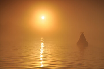 Buoy on the river against the background of the rising sun