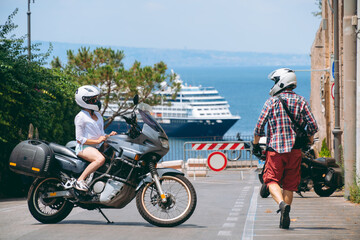 Obraz premium Man and woman. Love and relationships. Tourism and travel. Motorcycle for tours around the world. Street of sunny Italy. Ocean liner at sea in the background. Sorrento