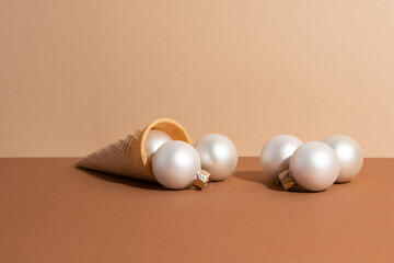 The ice-cream waffle cone on beige surface with white christmas balls. Holiday concept.