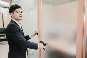 a new manager opens the door to his office in a strict business suit, Caucasian appearance, short...