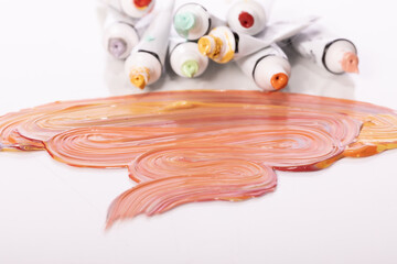 Several open tubes of colorful acrylic paint lying on glass table close up. Wide strokes of paint...