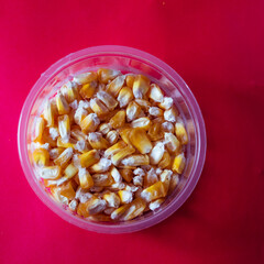Some corn in a plastic bowl.