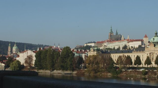 View over the Vltava River to Prague castle, St. Vitus Cathedral, Straka Academy and Petrin in Prague, pan right to left