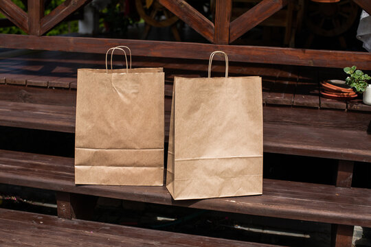 Two Brown Carton Paper Bags With Handles On Wooden Stair Steps. Contactless Delivery Of Goods And Products During Covid-19 Epidemic. Home Delivery Of Grocery Bags Left At Door For Spreading Safety.