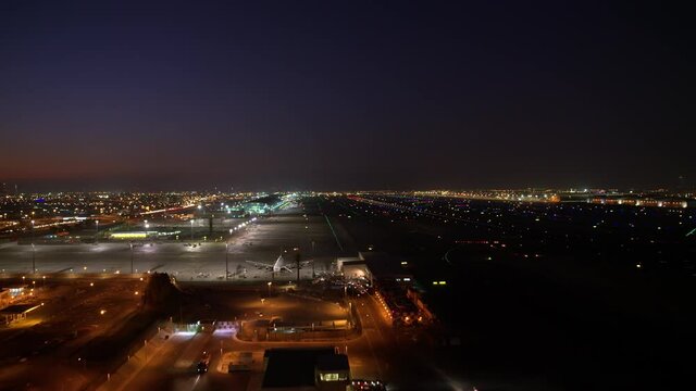 An amazing aerial view of Dubai airport night view. wide-angle parallax around the airport full of lights and color 6-axis stabilized gimbal, Shotover F1, 8K, zoom in and out, parallax,
