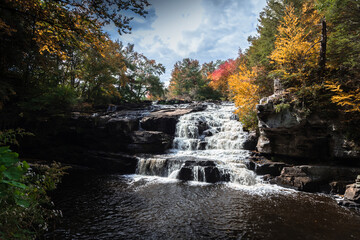 Fototapeta na wymiar Brilliant fall foliage surrounds the beautiful cascading Shohola Falls in the Pennsylvania Poconos