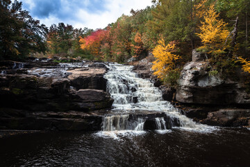 Fototapeta na wymiar Brilliant fall foliage surrounds the beautiful cascading Shohola Falls in the Pennsylvania Poconos