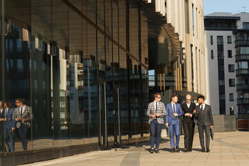 Business colleagues talking to each other during their walk in the city with modern buildings in the background