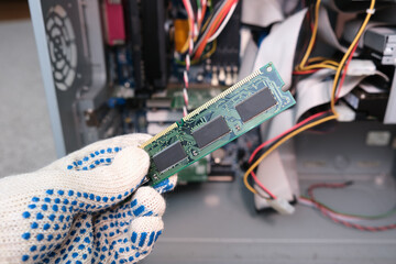 A hand of a repairer technician holding RAM, random access memory in order to upgrade an old...