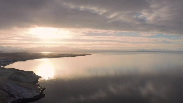 Amazing Sun Setting over Snow Capped Mountains in Distance, over Calm Icelandic Ocean Waters, Drone Aerial