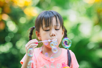 Cute kid blowing bubbles soap in the garden. Concept of digital free or unplugged outdoors activity...