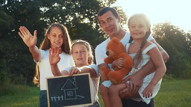 happy family in the park dreaming of their mortgage home. house concept home insurance. parent with kid in the park hold a sign symbol house. friendly happy family lifestyle concept
