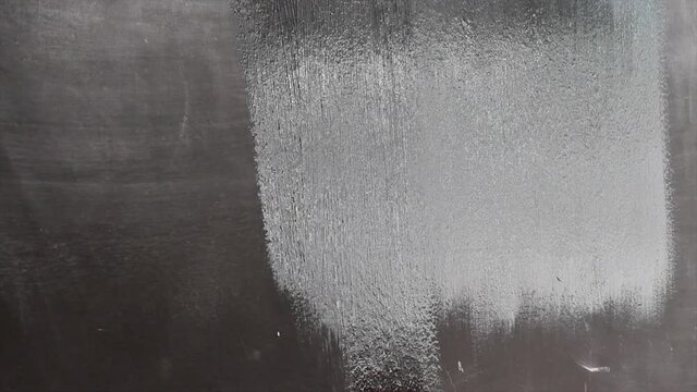 primer plano de mano pintando de negro una pared pizzarra para tiza
