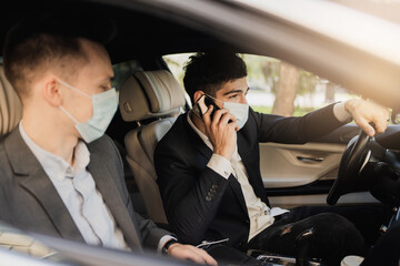 managers and coronavirus, pandemic, epidemic, infection. Sitting in the car wearing protective masks from covid 19, talking about work, strict business suits