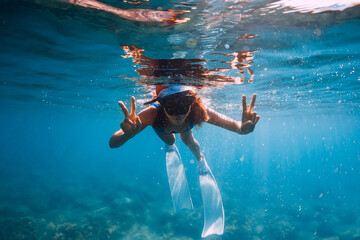 Happy freediver woman with New year cap glides underwater in blue ocean. Christmas holiday concept