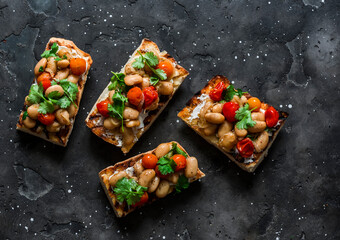 Goats cheese crostini with garlicky beans on a dark background, tp view. Delicious tapas, appetizers