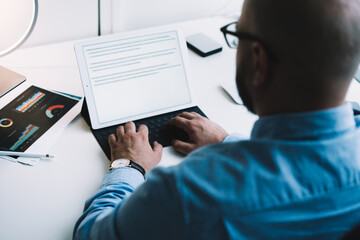 Crop businessman working on tablet