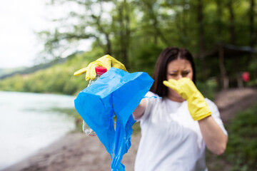 Female volunteer cleans the river shore