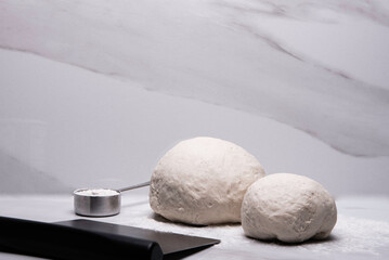 Pizza dough balls with flour and cutter on marble