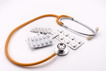blisters of pharmaceutical medicines in capsules and pills for therapy and stethoscope on the white background