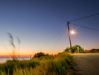 Old road with shining lantern during sunset phase and blue sky background