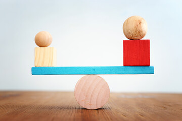 Concept of finding the right balance. Wooden balls and cubes on seesaw