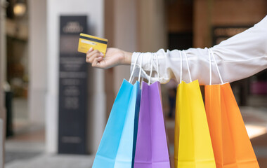Young women carry colorful shopping and use their credit card to shop at the mall