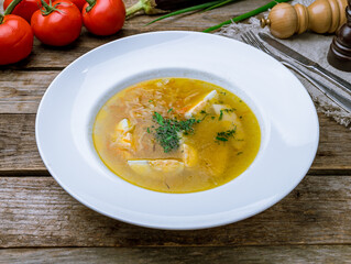 Chicken soup bouillon in a plate with homemade noodles on old wooden table