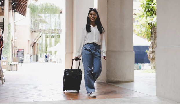 Asian woman beaming carrying a suitcase black to travel on vacation, Trolley bag, Long weekend travel, Love the trip, Tourism festival concept.