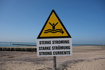 Strong current sign on beach with blue sea in the background
