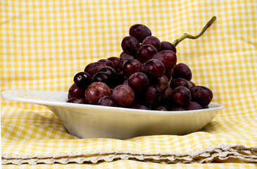 bunch of red organic grapes on a tray and tableclothbackground
