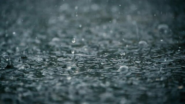 Super slow motion close up of rain hitting a puddle during a suburban storm.