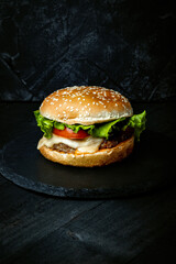  Fresh homemade burger with cheese and cutlet on black background, vertical photo