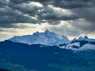 Fototapeta na wymiar Distant view of the snow covered Santis peak, the highest mountain in the Alpstein massif of northeastern Switzerland