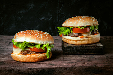  Two fresh homemade burgers with cheese and cutlet on a wooden board