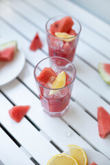 Fresh summer watermelon drink in a glass glass and a piece of watermelon on a wooden board. Vertical photo orientation