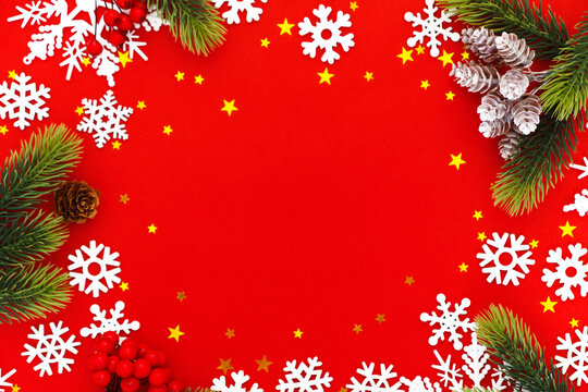 Christmas background with tree branches and snowflakes on red canvas background