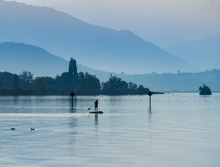 Standup Paddleboarding early in the morning on ithe dyllic shores of the Upper Zurich Lake (Obersee) between Hurden (Schwyz) and Rapperswil (St. Gallen), Switzerland