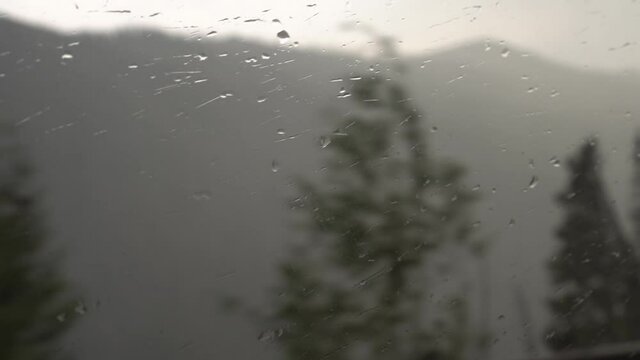 Raining on a car window through a national park.