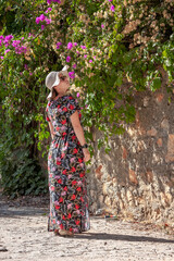 A girl stands near a wall and flowers on a tree