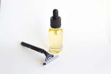 Disposable black razor and dropper glass bottle with essential oil