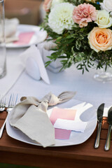 place cards for with the guest's name on the plate. dinner tables with white cloth, served with...
