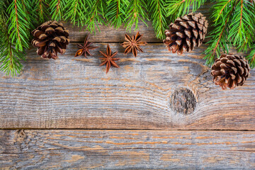 Christmas wooden background with fir branches and cones, top view with copy space