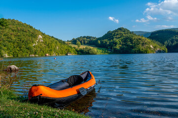 An inflatable kayak on the shore of the Zaovine lake in Serbia with beautiful mountain landscape in the background