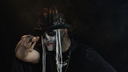 Man in skeleton Halloween cosplay costume. Guy in creepy skull makeup making faces, looks mysterious