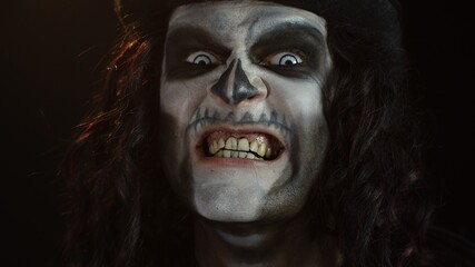 Frightening man in skeleton Halloween makeup screaming, shouting, making faces, trying to scare