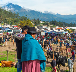 Unrecognizable indigenous Ecuadorian Otavalo woman with her son looking over the traditional animal...