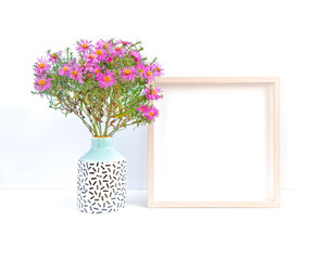 Autumn flower arrangement. A bouquet of octobrin flowers (Aster perennial) and an empty wooden photo frame are on a white background. Flat lay. Top view. Copy space.